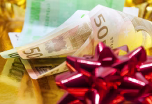 Po izplačani božičnici od delavca zahteval, da mu jo vrne v gotovini Money with a red gift bow on golden background