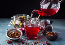 Kaj vaš najljubši čaj pove o vaši osebnosti? Process brewing tea, tea ceremony, Cup of freshly brewed fruit and herbal tea, dark mood .Hot water is poured from the kettle into a cup with tea leaves.