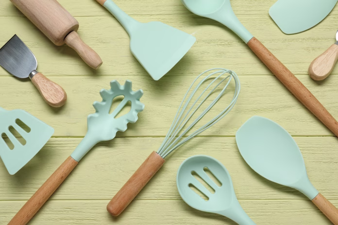 Set of different kitchen utensils on yellow wooden table, flat lay