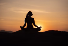 Prednosti meditacije, zaradi katerih se je mnogi poslužujejo Silhouette of sport woman striking a graceful yoga pose against the glowing. This image perfectly represents the essence of meditation, wellness, and the pursuit of balance in life.