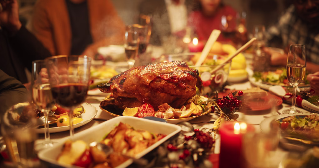 Tastefully Decorated Christmas Banquet Dining Table with a Grilled Turkey Dish, Vegetable and Fruit Meals, Baked Potatoes, Desserts and Drinks. Establishing Shot Without People