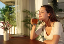 Kateri čaj najbolj sprošča? Woman at home relaxing smelling tea at sunset