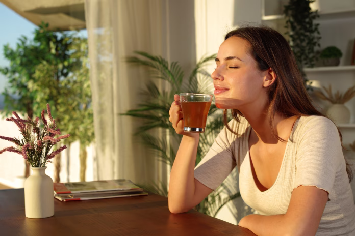 Woman at home relaxing smelling tea at sunset