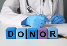 20 ljudi na dan umre po nepotrebnem: Krivo pa tole … Word Donor made of wooden cubes. Doctor writing in notebook at white table, closeup