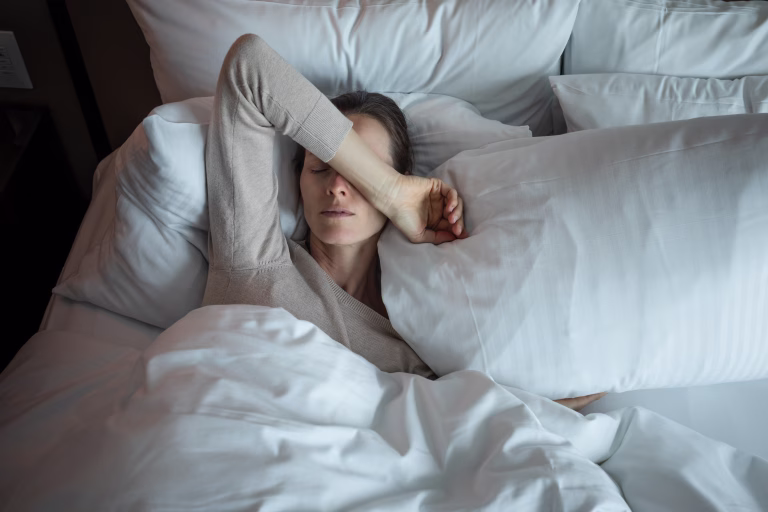 Young woman waking up and feeling tired (suffering from insomnia).
