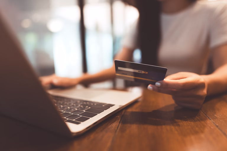 Business people shopping via online payment and digital wallet concept. Woman hand consumer using creadit card or debit and laptop on wooden table.