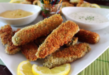 Ocvrte kisle kumarice: čudaški prigrizek iz cvrtnika na vroči zrak Deep fried dill pickles, with dipping sauce, and sour cream and chives. White plate and bowls, colorful toothpicks.