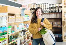 Kateri izdelek je bolje kupiti? Na voljo imate lokalno in fair-trade … Happy woman carrying vegetables in bag at supermarket