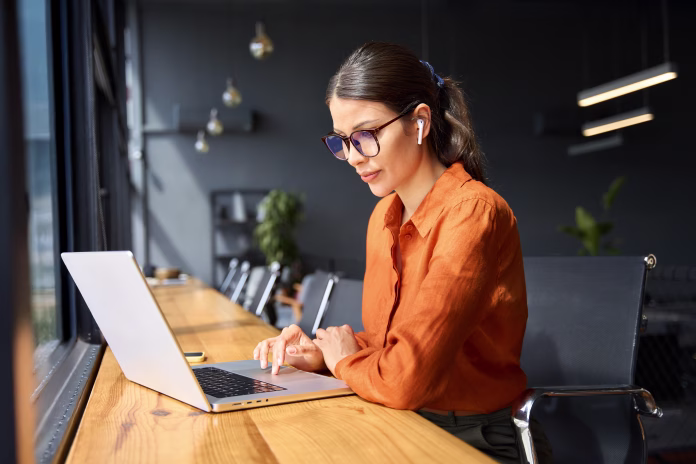 Indian entrepreneur manager businesswoman using pc for communication, learning at workplace. Focused latin hispanic young business woman working on laptop computer sitting at office workplace desk