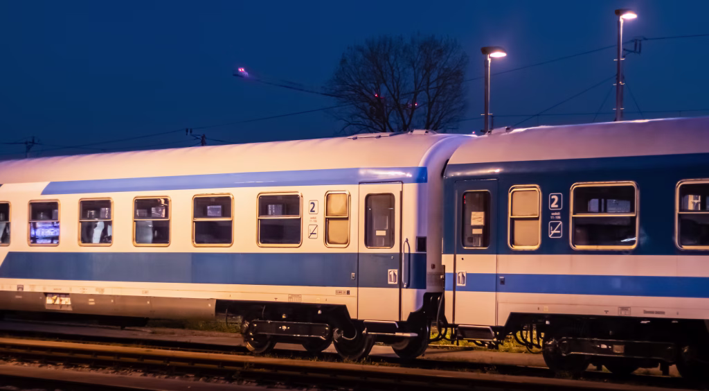 Ljubljana, Slovenia November 10, 2025 blue and white passenger train standing at a night station under artificial lights with empty platform and dark sky in the background
