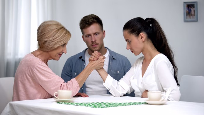 Man looking at mother and wife during arm wrestling competition, family fight