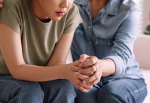 TEGA nikoli ne recite osebi, ki je izgubila bližnjega Middle aged asia people old mom holding hands trust comfort help young woman talk crying stress relief at home. Mum as friend love care hold hand adult child feel pain sad worry of life crisis issues.