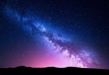 Posneli prelomno fotografijo Rimske ceste Milky Way and pink light at mountains. Night colorful landscape. Starry sky with hills at summer. Beautiful Universe. Space background with galaxy. Travel background