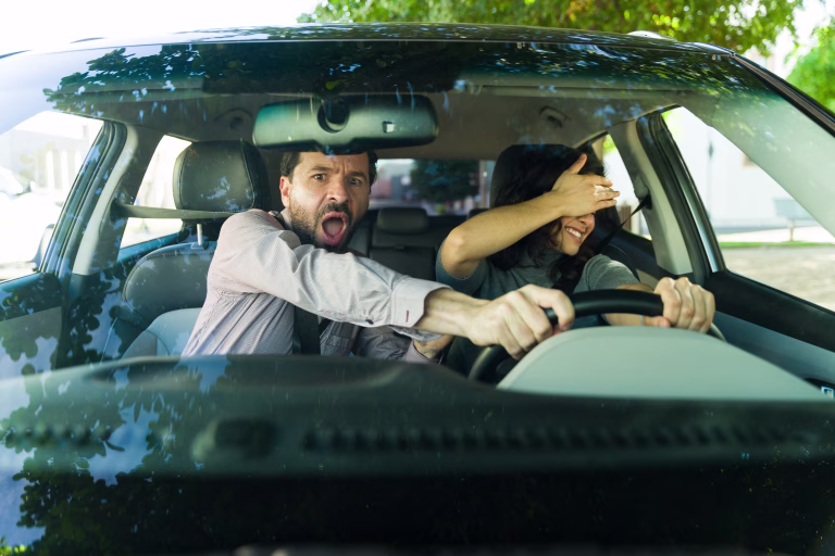 Nervous adult driving instructor reacting to a reckless female student driving, causing a dangerous and fearful moment during a lesson