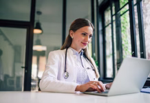 Od marca nov način komuniciranja z zdravniki Positive doctor working on computer in medical office, portrait.