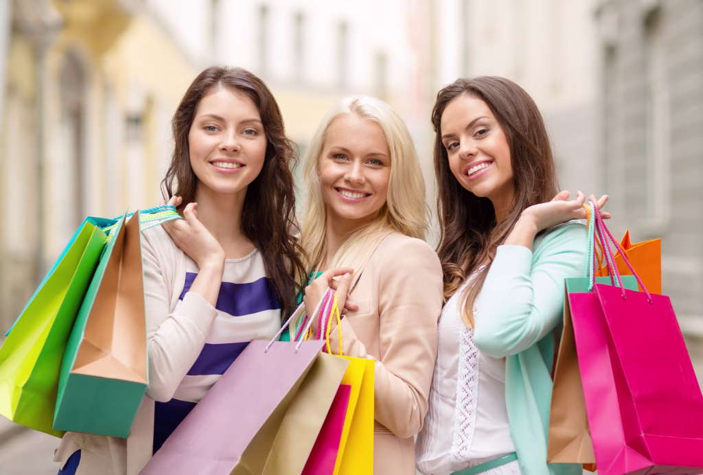 shopping, sale, happy people and tourism concept - beautiful girls with shopping bags in ctiy