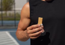Slabosti proteinskih ploščic Sports man eating energy bar. Muscular athlete snacks on protein bar while resting after workout at stadium. Healthy protein snack or energy bar, fitness dieting food for sporty lifestyle.