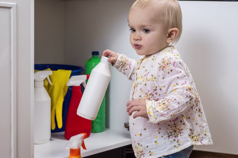 Toddler playing with household cleaners at home