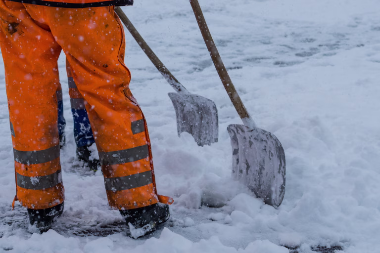 Workers sweep snow from road in winter, Cleaning road from snow storm