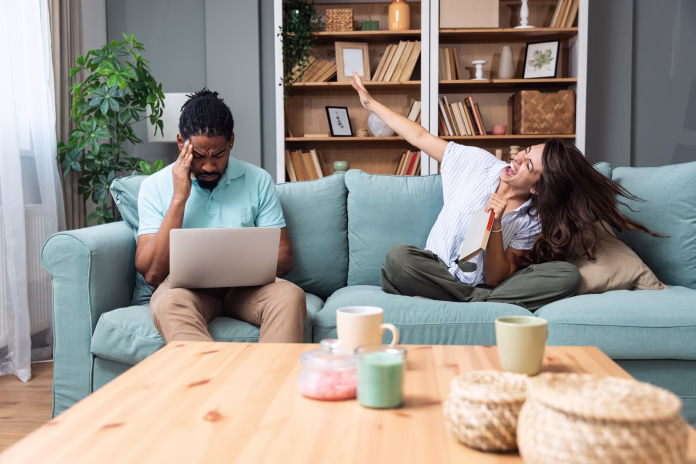 young-woman-having-fun-and-trying-to-distract-her-boyfriend-working-from-home-online-on-laptop-freelance-man-work-on-a-computer-remotely-via-the-internet-and-his-girlfriend-is-acting-crazy-and-funny-stockpack-istock Young woman having fun and trying to distract her boyfriend working from home online on laptop. Freelance man work on a computer remotely via the Internet and his girlfriend is acting crazy and funny
