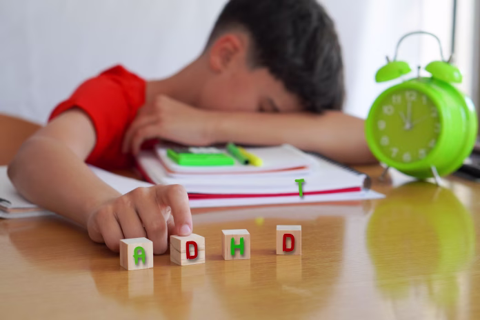 child surrounded by books and notebooks frustrated, with the acronym ADHD, represents the disease Attention Deficit Disorder and the difficulties it entails in school life.
