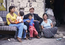 Varuh zahteva zadržanje Šutarjevega zakona: »Mladoletni člani družin niso odgovorni za nastanek dolgov svojih staršev« KAGITHANE GULTEPE, ISTANBUL, TURKEY - AUG. 2008: Group portrait of a poor Turkish (roman) gypsy family sitting on the street in front of their ruin shanty house. Editorial use only.
