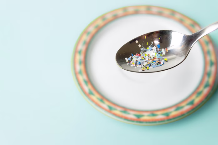 Microplastics in food. Problem of plastic particles in food, Concept, Health problems, cancer, kidney diseases and Environmental pollution. contaminated spoon and copy space.