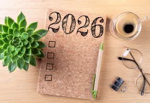Pravilo 90/90/1: tako uresničite dolgoročne cilje New year resolutions 2026 on desk. 2026 goals list with notebook, coffee cup, plant on wooden table. Resolutions, plan, goals, action, checklist, idea concept. New Year 2026 resolutions, copy space