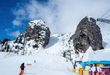 Zimske OI Milano Cortina 2026, kdo in kdaj nastopa ter kako je s prenosi? Olympic downhill ski run Olimpia 1 in Cortina dAmpezzo in Dolomites, Italy. The steepest part between big rocks. Ski lift and unrecognizable skiers. Slope often used for Alpine ski World Cup races