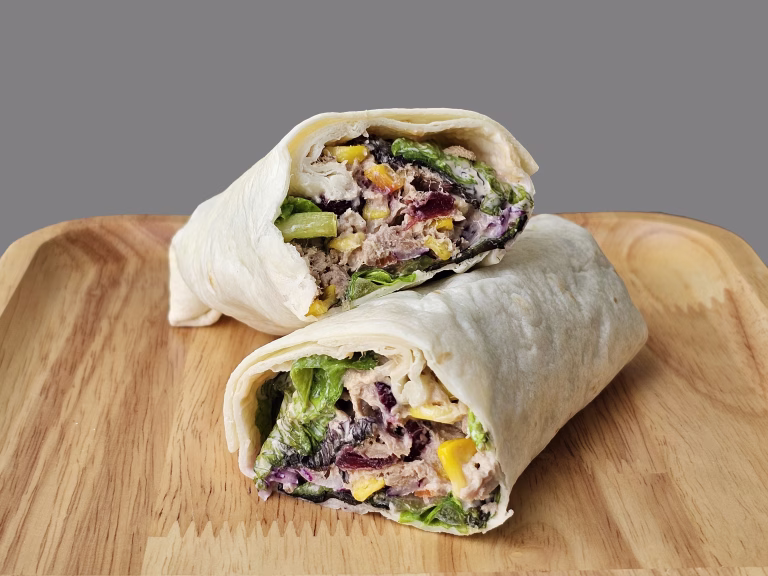 Tortilla wrap with tuna and vegetables on wooden plate