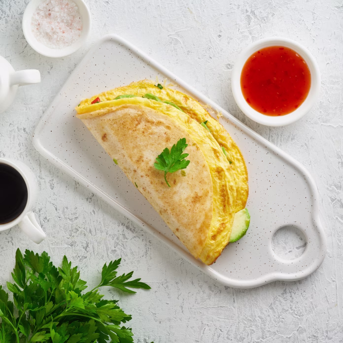 Trendy breakfast with quesadilla and eggs, trending food with omelet, cheese, peppers, tomatoes, avocado. Simple and easy lunch, top view