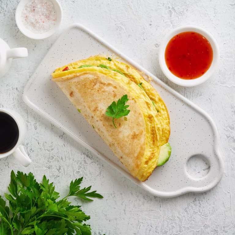 Trendy breakfast with quesadilla and eggs, trending food with omelet, cheese, peppers, tomatoes, avocado. Simple and easy lunch, top view
