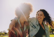 Postanite boljši prijatelj: 5 nasvetov, ki jih morate upoštevati Two best friends laughing and enjoying each other's company on a summer's day in the park. Happiness and friendship in a natural outdoor setting.