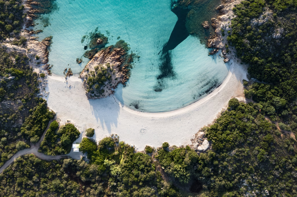 View from above, stunning aerial view of a green coast with the beautiful Prince Beach (Spiaggia del Principe) a white sand beach bathed by a turquoise water. Sardinia, Italy.
