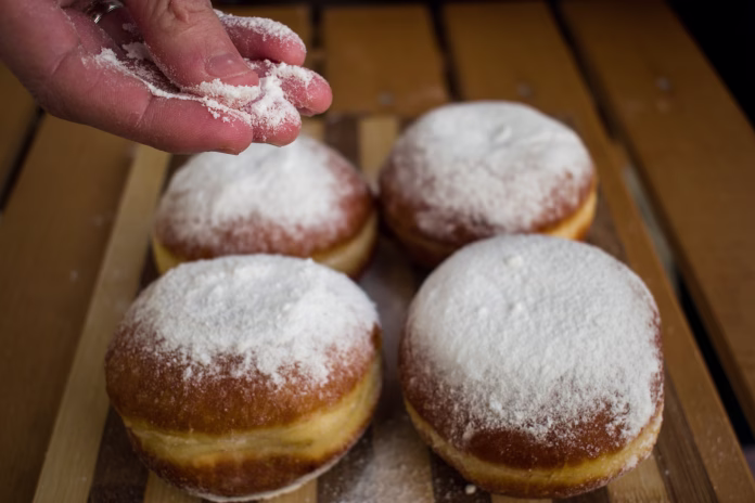 Woman hand sprinkle with powdered sugar homemade donuts