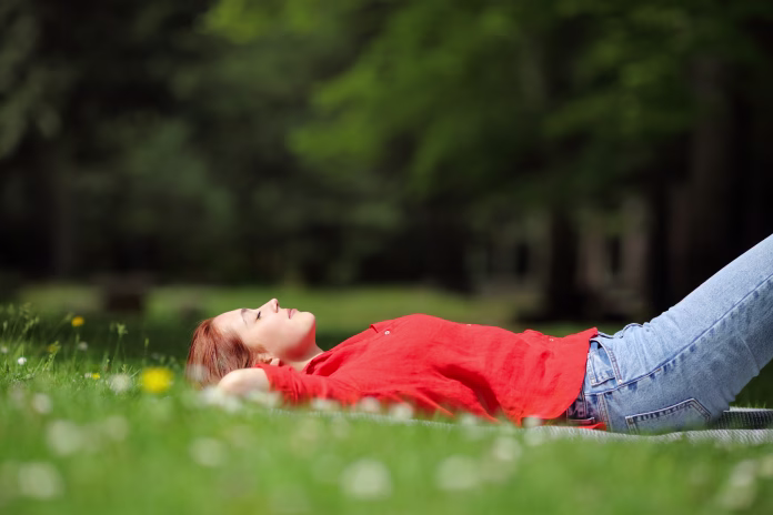 Woman resting lying on the grass in a park or forest