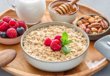 12 živil, ki imajo več vlaknin od ovsenih kosmičev Bowl of porridge or oatmeal with different ingredients on wooden tray. Breakfast serving.