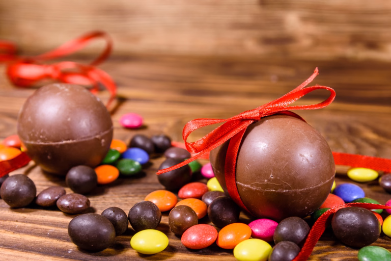 Chocolate easter eggs and multicolored candies on rustic wooden table
