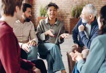 Kaj je socialna inteligenca in kako jo lahko povišate? Diverse group of people sitting in a circle during a group therapy session, actively listening to a doctor who is facilitating the discussion