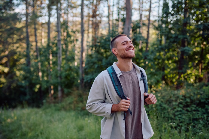 Happy hiker breathing in fresh air while enjoying a trekking day in the serene woods, embracing the beauty of nature and adventure