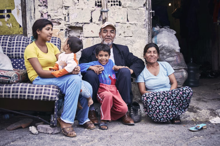 KAGITHANE GULTEPE, ISTANBUL, TURKEY - AUG. 2008: Group portrait of a poor Turkish (roman) gypsy family sitting on the street in front of their ruin shanty house. Editorial use only.