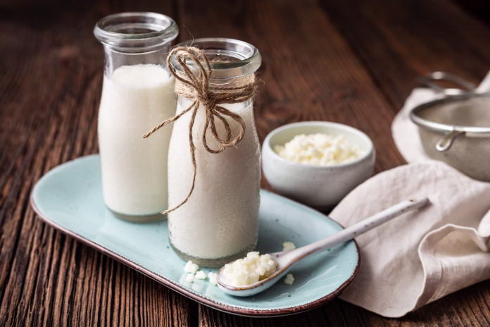 Kefir, healthy probiotic beverage with milk kefir grains on wooden background