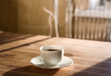 Tako kava vpliva na zdravje vašega črevesja – presenetilo vas bo Kitchen interior in natural light, wood table with hot steaming drink on it