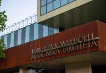 Omejitev vpisa je več kot lani, največjih jih ima ta univerza: prebrskali smo rezultate prvega prijavnega roka Maribor, Slovenia - August 9, 2025: A close-up architectural shot of the University of Maribor's Faculty of Medicine entrance. The image highlights the contemporary design featuring 3D metal lettering mounted on a textured, rusty Corten steel panel, contrasting with sleek glass windows. Perfect for educational articles, medical brochures, and architectural portfolios showcasing modern European university campuses.