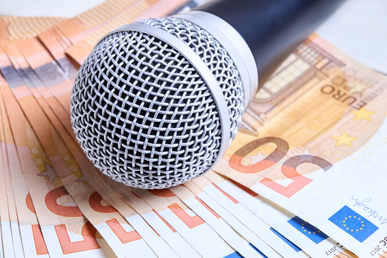 Microphone over euro bills background close up shot. Microphone lies on scattered euro banknotes. Concept of karaoke club, artist fee, payment for performance, professional musicians career.