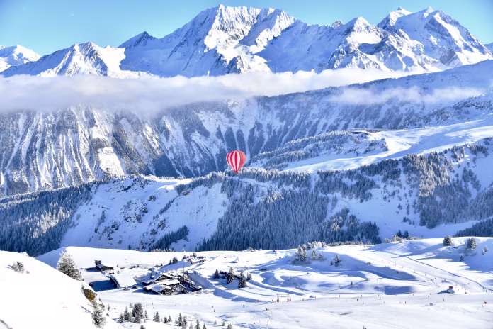 Red hot air balloon in blue sky in french Alps by winter