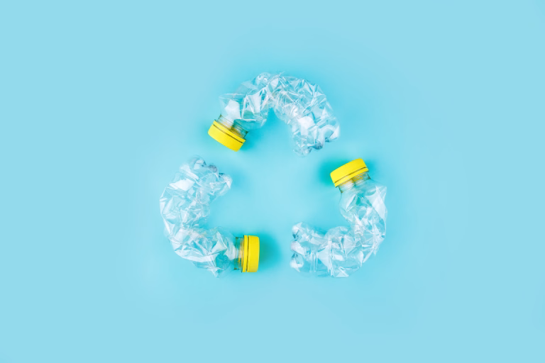 Three crashed plastic bottles on blue background form resycling sign. Plastic utilisation concept. Attractive ecological problem positive poster.