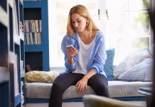 Kako na lep način odpovedati skupne plane? Woman Sitting On Couch At Home Using Mobile Phone