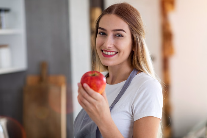 Young woman holding an apple and smiling