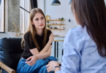 Kako v Sloveniji deluje zdravstveni sistem za mednarodne študente? Young woman talking to social worker, home meeting, home visit of psychological counselor, survey consultation. Social services, psychology psychotherapy help treatment support, mental health, youth